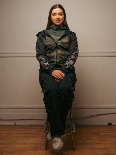 Anishinaabe Bimishimo founder Emilie McKiney sits on a stool.